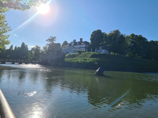 Das Schloss in Bad Pyrmont, strahlende Sonne im Gegenlicht. Es ist umgeben von einem großen Wassergraben.